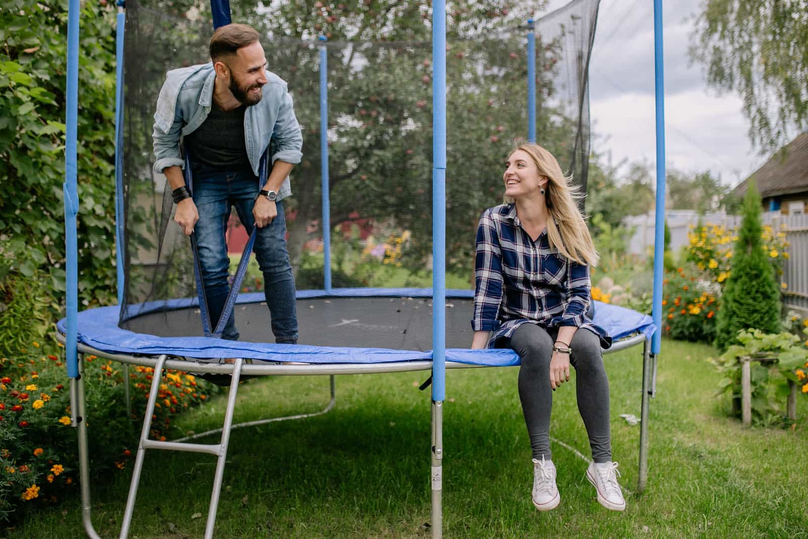 Smiling couple sitting on a trampoline surrounded by greenery and flowers