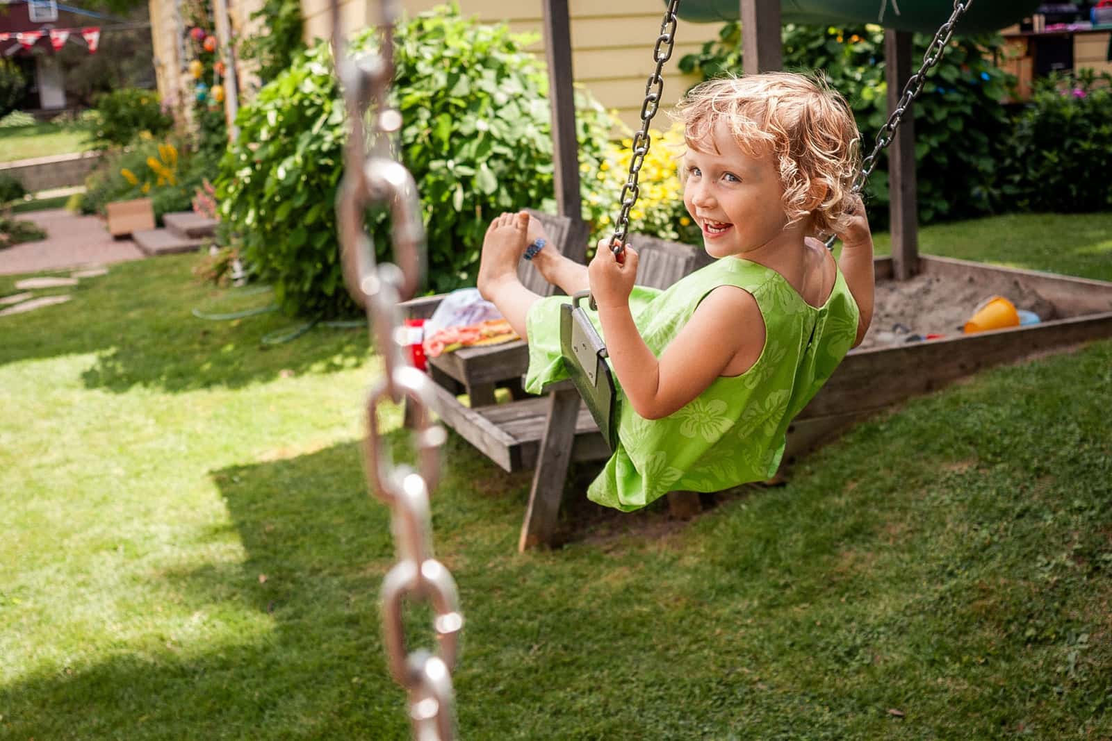 Child swinging in a backyard garden on a sunny day