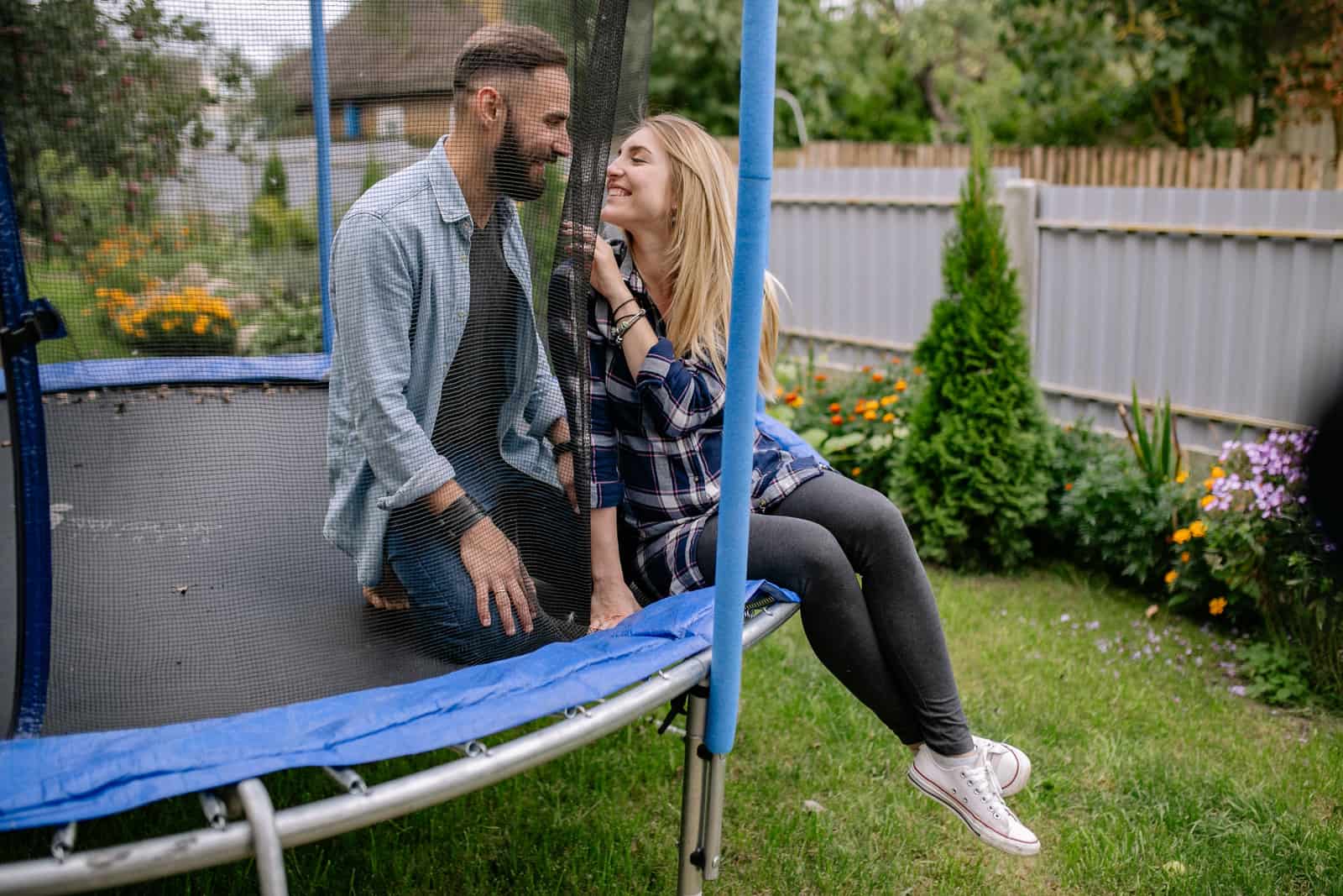 Couple smiling together on a backyard trampoline surrounded by greenery