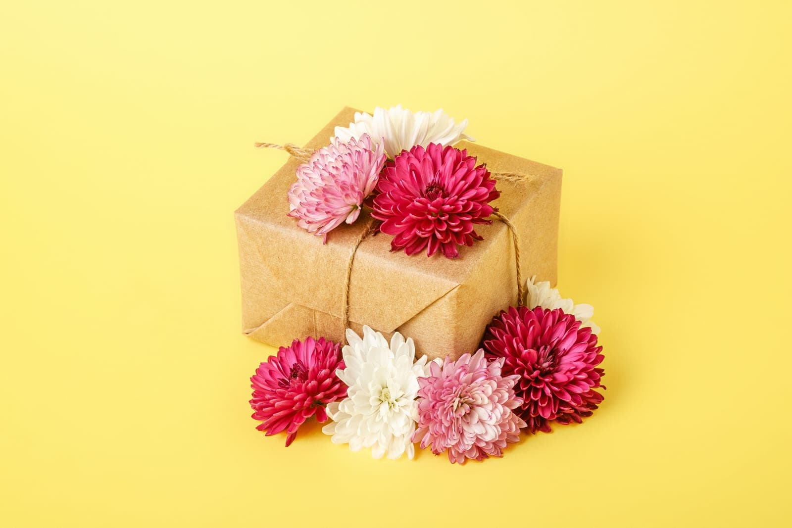 Gift box decorated with red and white flowers on a yellow background