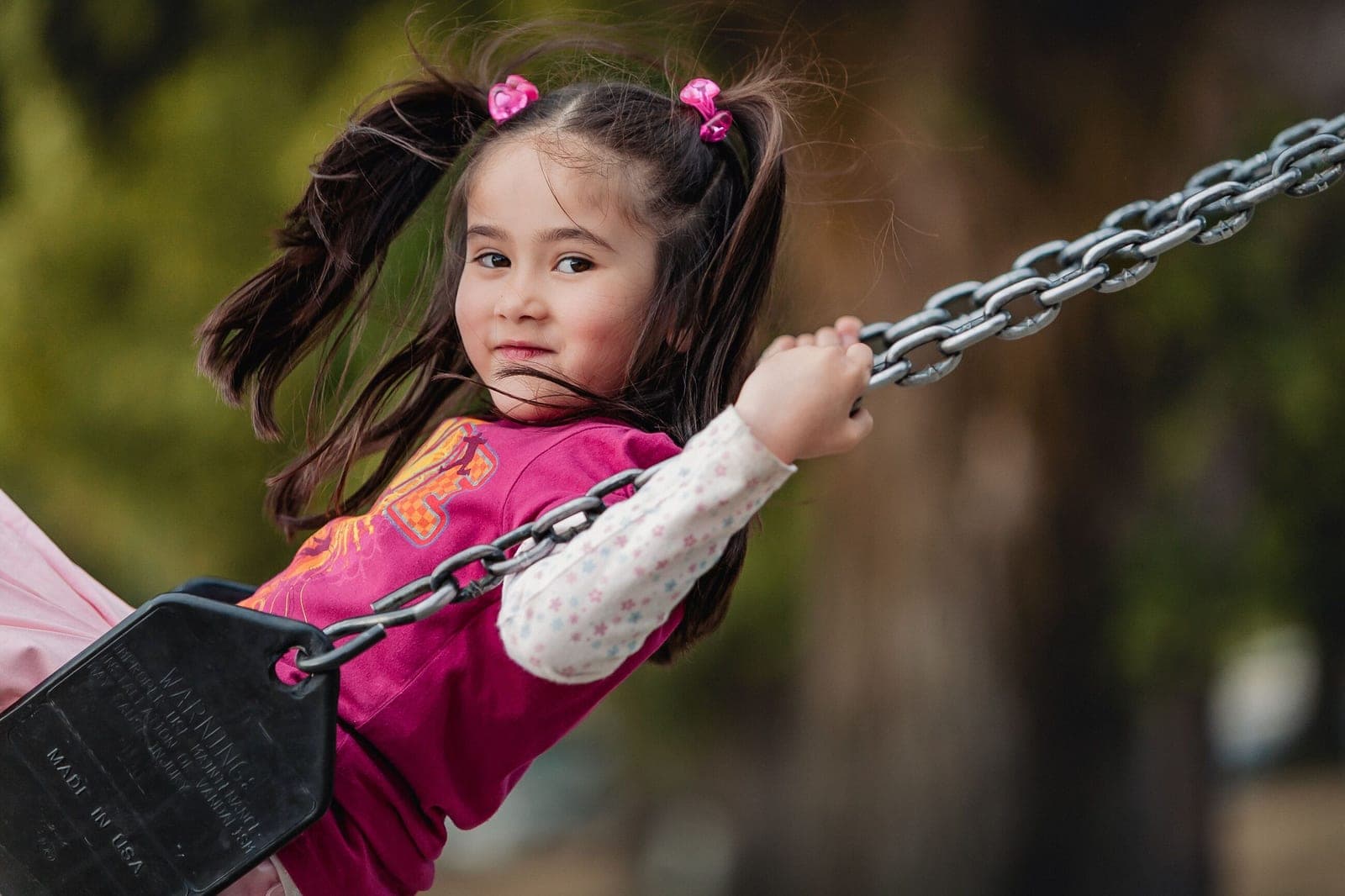 Young girl with pigtails smiling on a swing outdoors
