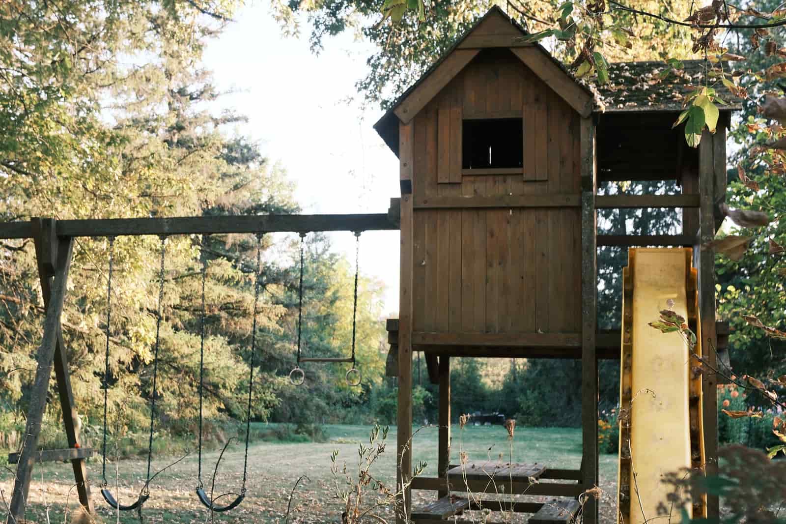 Wooden playground with swings and a slide in a quiet forest setting