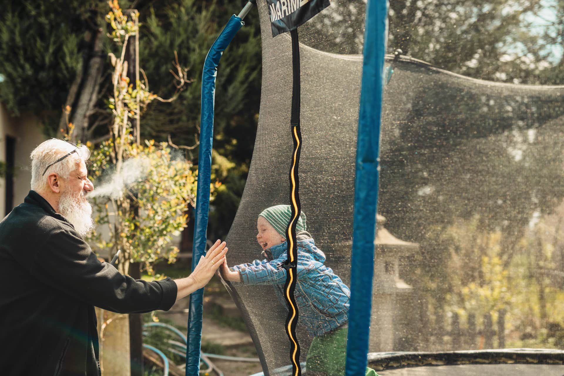 Grandfather and grandson playing on a trampoline in the sun