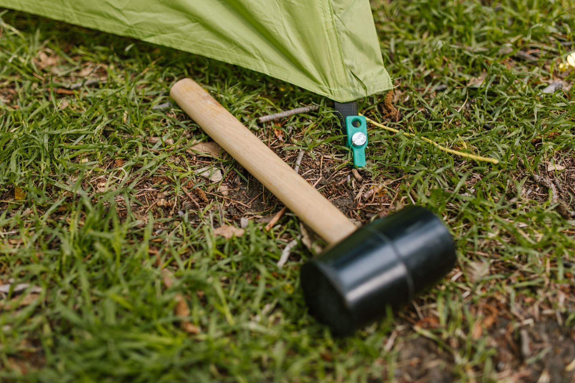 Rubber mallet lying on grass next to a ground stake