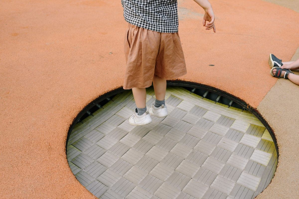 Child jumping on an outdoor trampoline with a safety net