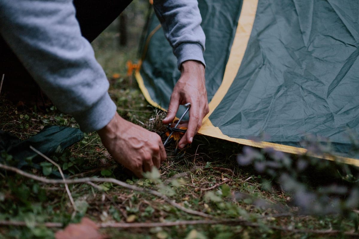 Person pressing a ground peg into soil with their hands