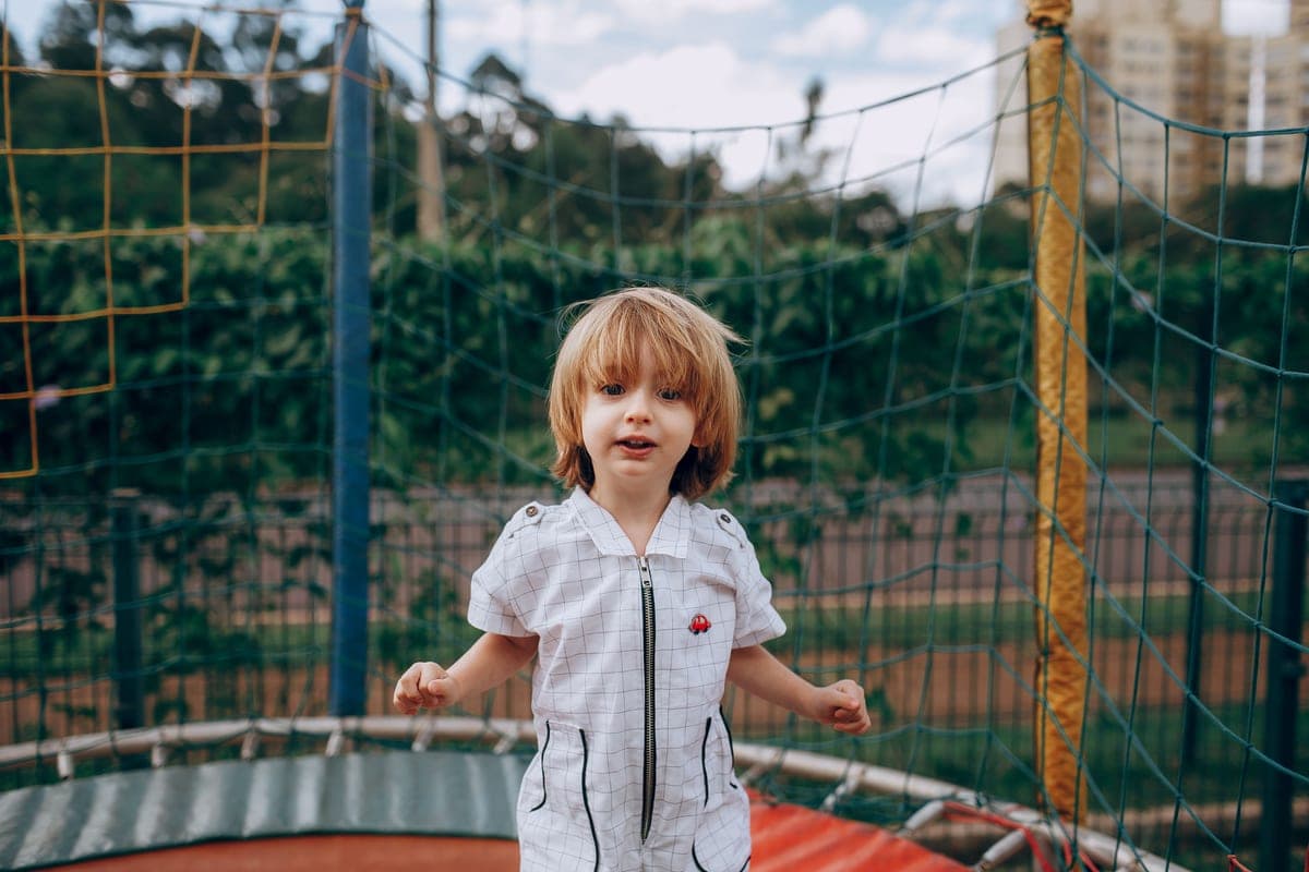 Young child standing on a trampoline in a park in summer